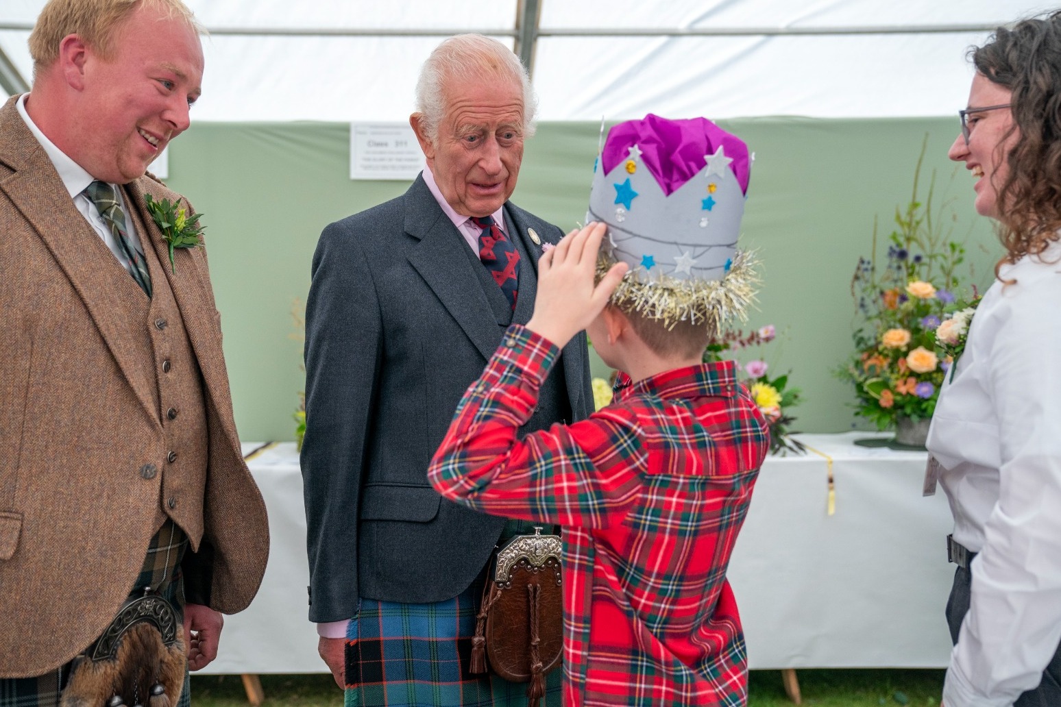 Schoolboy tries on prize-winning cardboard crown in front of the King 